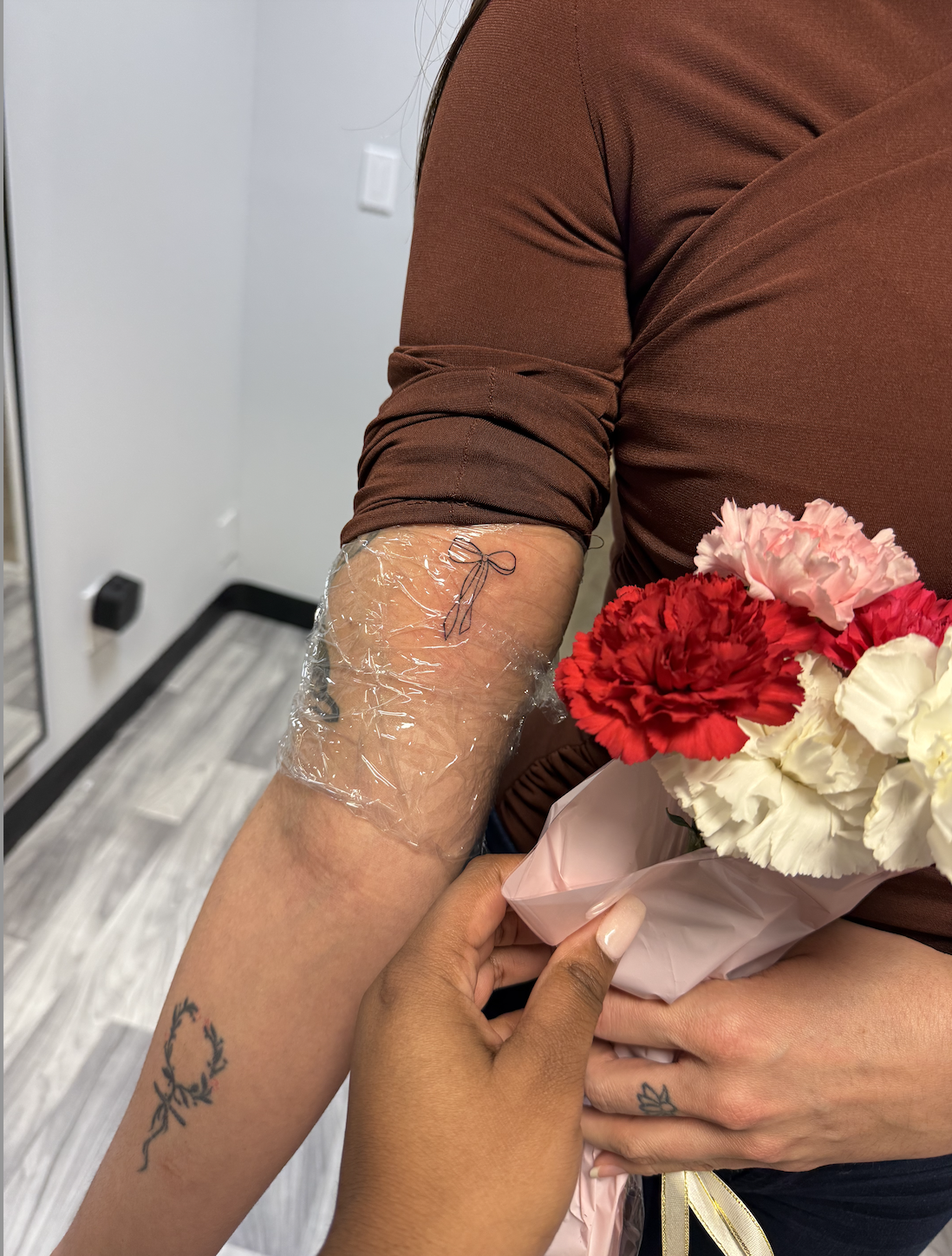 A guest with a fresh fine-line tattoo and bouquet at a Good Anatomy experience.